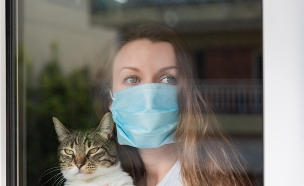 אישה עם מסכה מסתגרת בביתה בשל התפרצות קורונה (צילום: 22Images Studio, shutterstock)