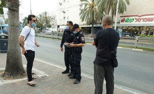 שוטרים קונסים אדם שלא הלך עם מסיכה לפי ההוראות בחולון (צילום: Roman Yanushevsky, shutterstock)