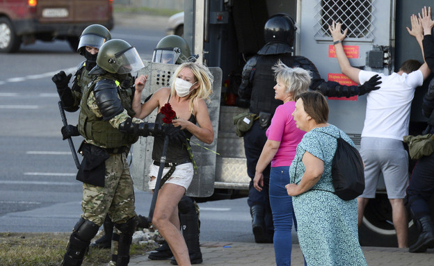 אישה נאבקת בשוטר שעוצר תומכי אופוזיציה שמפגינים במינסק (צילום: ap)