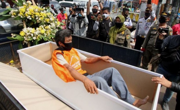 אזרח בארון קבורה, לאחר שנתפס ללא מסכה (צילום: BBC)