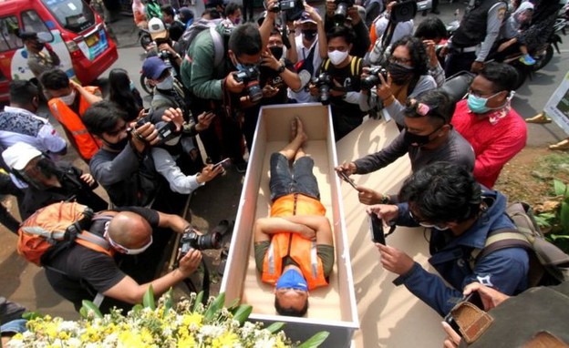 אזרח שוכב בארון קבורה - לאחר שנתפס ללא מסכה (צילום: BBC)
