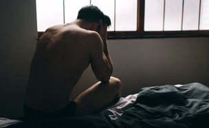 גבר יושב על המיטה בדיכאון (צילום: Estrada Anton, Shutterstock)