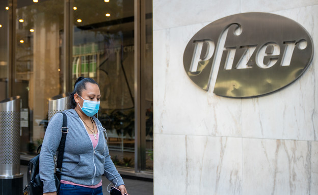 אישה עם מסכה חולפת ליד הבניין המרכזי של חברת פייזר (צילום: David Dee Delgado, getty images)