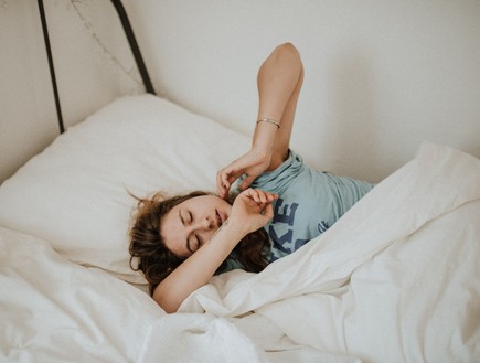 אישה מתעוררת במיטה (צילום: kinga-cichewicz-unsplash)