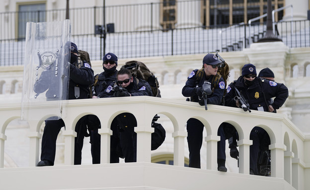 שוטרי הקפיטול מכוונים נשקים לכיוון המפגינים במטרה למנוע מהם להיכנס (צילום: AP)