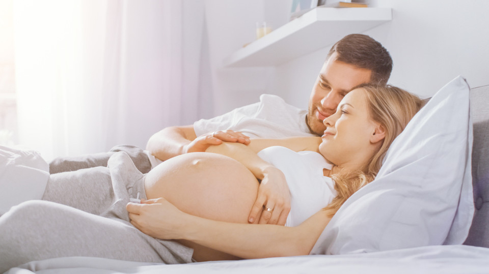 אישה בהיריון עם בן זוגה במיטה (אילוסטרציה: Gorodenkoff, shutterstock)