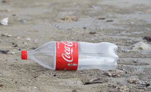 בקבוק קוקה קולה זרוק בחוף (צילום:  Fazly Marijal, shutterstock)