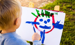 ילד מצייר ציור עם מכחול מצולם מגבו (צילום: RapidEye, Istock)