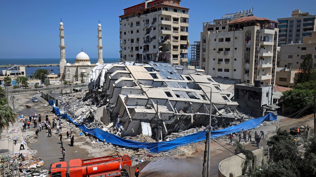 מתנדבים מנקים הריסות של בניין שהופצץ בשכונת רימאל בעזה
