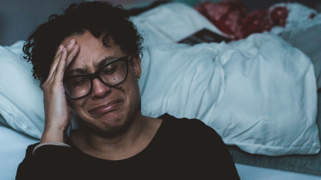אישה בוכה ליד מיטה (אילוסטרציה: Claudia wolff, unsplash)