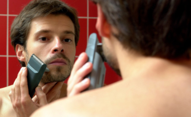 גבר מתגלח במכונה מול מראה (צילום: אור גץ, istockphoto)