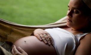 אישה בהיריון מניחה יד על הבטן בשל תחושת צירים (צילום: istockphoto)