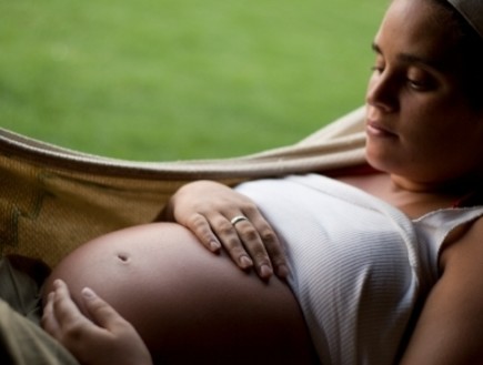 אישה בהיריון מניחה יד על הבטן בשל תחושת צירים (צילום: istockphoto)