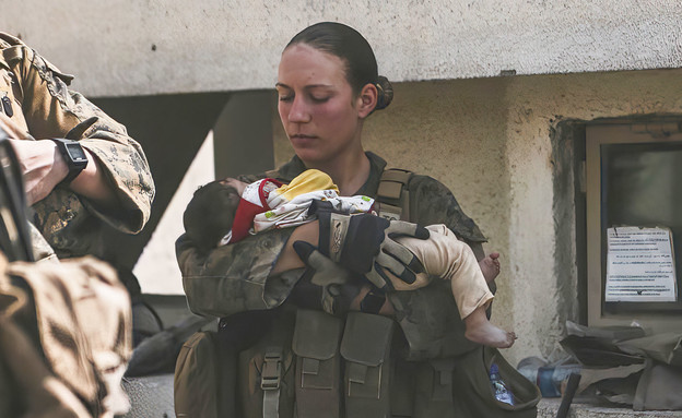 החיילת האמריקאית ניקול ג'י מרגיעה תינוקת אפגנית  (צילום: ap)