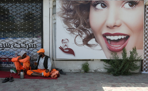 שני עובדי עירייה נחים בקאבול על רקע פרסומת (צילום: רויטרס)