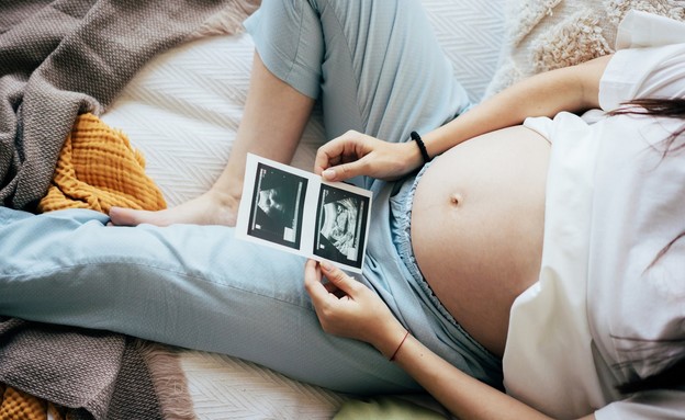אישה בהיריון מסתכלת על בדיקות אולטרהסאונד (אילוסטרציה: Ilona Titova, shutterstock)