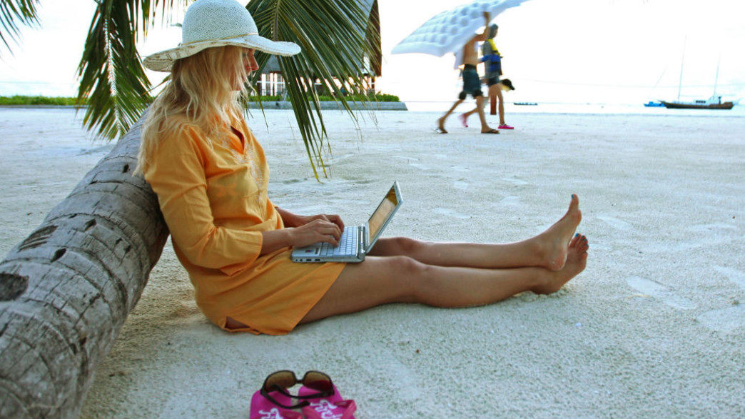 אישה עובדת עם לפטופ וטלפון סלולרי באתר נופש במלדיביים (צילום: EyesWideOpen, Getty Images)