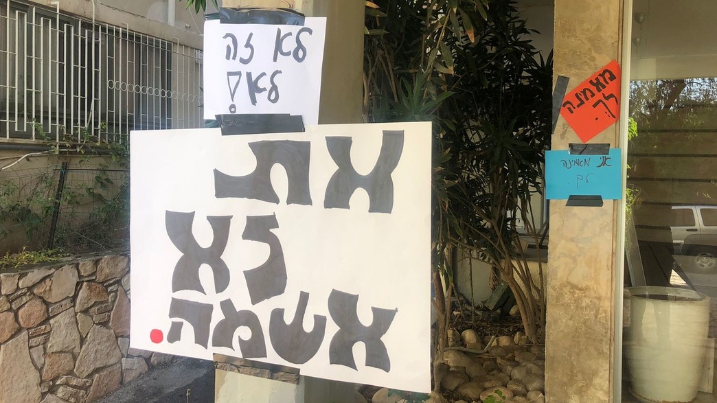 השלטים שנתלו מתחת לביתו של החשוד (צילום: איתי דגן , פרטי)