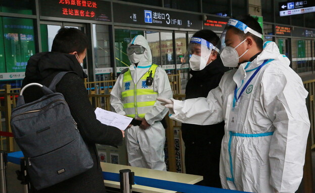 אנשי הצוות בודקים את המסמכים של נוסע בכניסה לתחנת רכבת בשיאן בסין  (צילום: רויטרס)