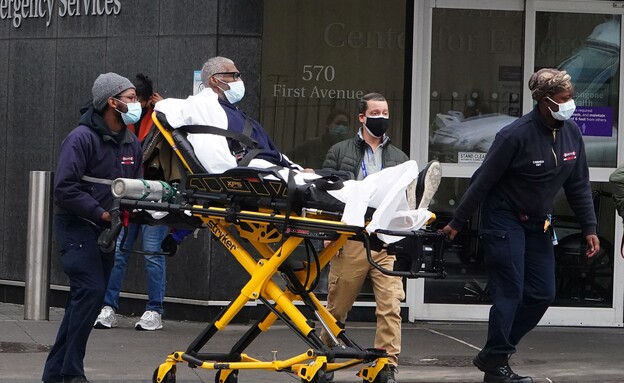 צוותים רפואיים בניו יורק מובילים חולה קורונה (צילום: רויטרס)