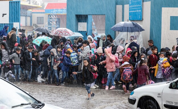 ילדים הולכים בגשם בעיר עזה, ינואר 2022 (צילום: MAHMUD HAMS/AFP, Getty Images)