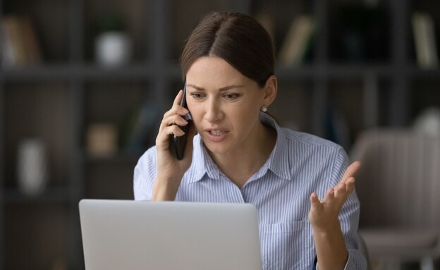 אישה מדברת בטלפון מול מחשב (צילום: shutterstock)