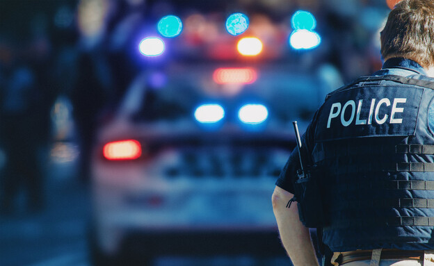 שוטר ליד ניידת משטרה (צילום: ALDECA studio, shutterstock)