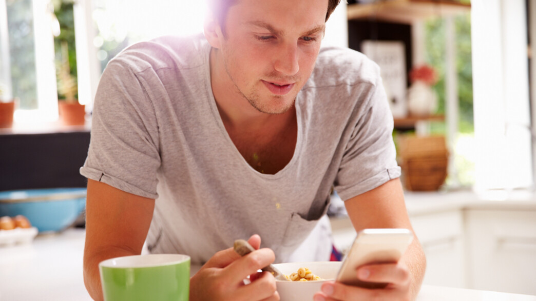 גבר אוכל ארוחת בוקר ומסתכל בטלפון סלולרי (צילום: By Dafna A.meron)
