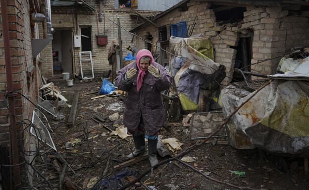 אישה מביטה בהריסות ביתה שנהרס כתוצאה מהפצצת הרוסים בפאתי קייב (צילום: AP)