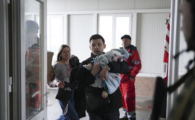 אב נושא את בנו התינוק שנהרג בהפגזה לבית החולים במריופול  (צילום: AP)