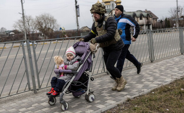 חייל אוקראיני עוזר בפינוי ילדה מהעיר אירפין (צילום: רויטרס)