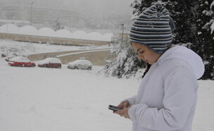 ילדה מסתכלת על הטלפון בשלג בירושלים (צילום: Dan Porges, Getty Images)