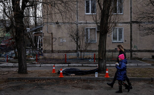 אישה וילד חולפים ליד גופת אדם ברחובות קייב (צילום: רויטרס)