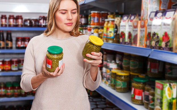 אישה בודקת צנצנות חמוצים בסופרמרקט אישה בודקת צנצנות חמוצים בסופרמרקט