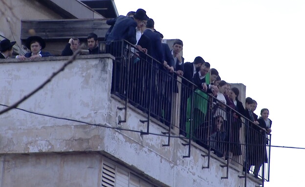 אנשים משקיפים במרפסות ליד בית הרב קניבסקי (צילום: N12)