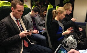 נוסעים ברכבת ללונדון מסתכלים על טלפוניים סלולריים ואייפד (צילום: John Keeble, Getty Images)