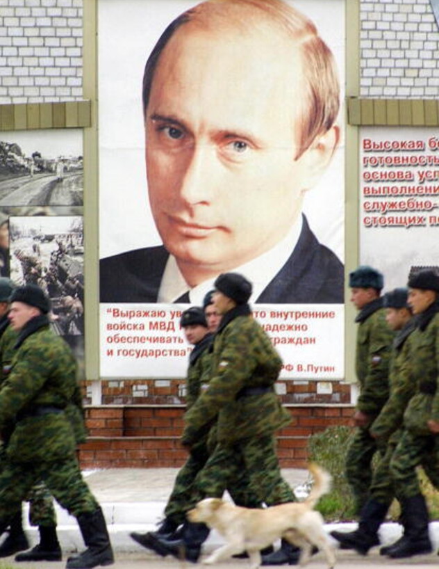 חיילים רוסים על רקע תמונתו של ולדימיר פוטין בצ'צ'נ (צילום: VIKTOR DRACHEV/AFP via Getty Images)