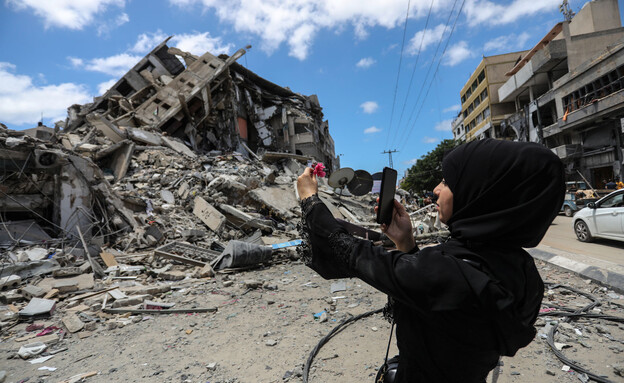 פלסטינית מצלמת בניין הרוס בעזה בעזרת סמארטפון (צילום: Ahmed Zakot/SOPA Images/LightRocket via Getty Images)