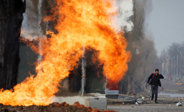A man passes by a burning gas pipe that was hit during a shelling (Photo: Reuters)