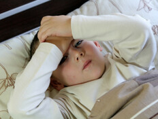 ילד שוכב במיטה ומחזיק את הראש (צילום: אימג'בנק / Thinkstock)