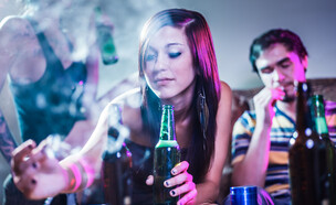 בחורה מעשנת קנאביס ושותה אלכוהול (צילום: Joshua Resnick, shutterstock)