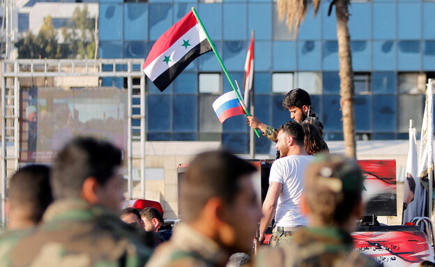 אזרחים סורים מניפים את דגלי רוסיה בסוריה (צילום: רויטרס)