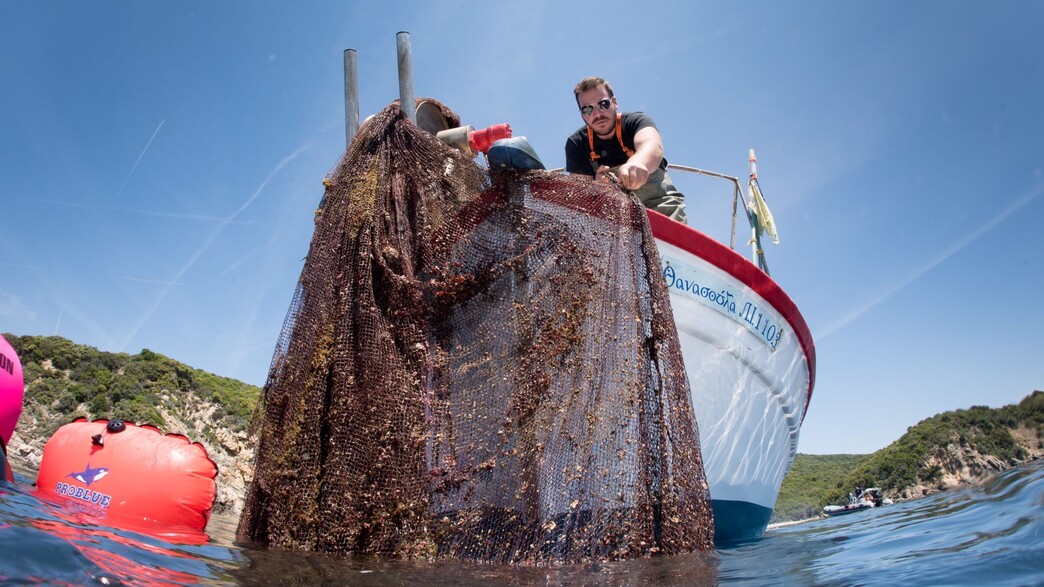 אדם מושך רשת רפאים מהמים בכפר סטראטוני שביוון
