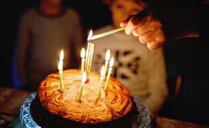 שני ילדים מסתכלים על עוגת יום הולדת עם שבעה נרות (אילוסטרציה: Irina Wilhauk, shutterstock)
