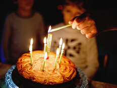 שני ילדים מסתכלים על עוגת יום הולדת עם שבעה נרות (אילוסטרציה: Irina Wilhauk, shutterstock)