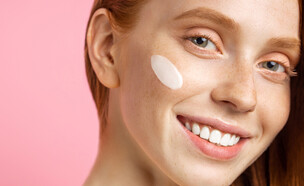 אישה עם שיער אדום מורחת קרם עיניים  (צילום: Stockshakir, shutterstock)