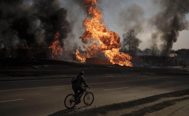 אדם בורח מלהבות באופניים, אוקראינה (צילום: AP)