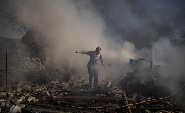 אדם הולך על הריסות בית, אוקראינה (צילום: AP)