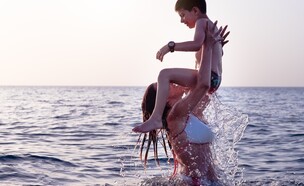 אמא משחקת בים עם בנה (צילום: PhotoMachinestudio, shutterstock)