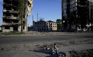 ילד משחק מול בית הרוס, אוקראינה (צילום: AP)